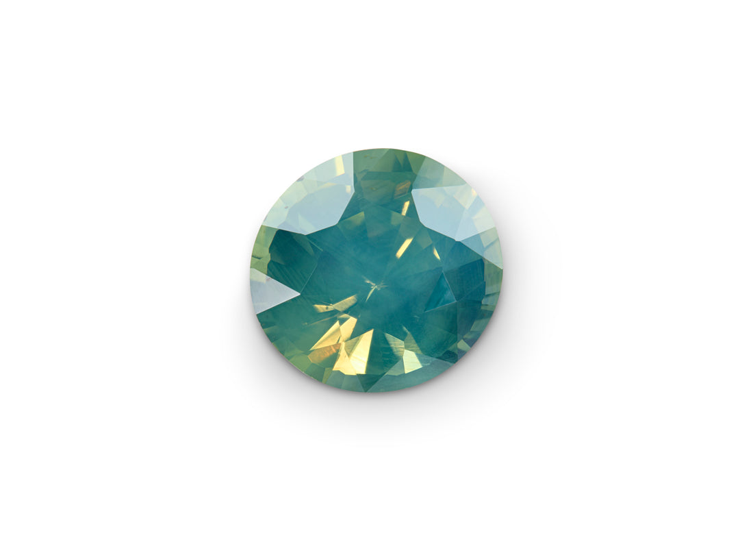 1.85ct Opalescent Teal Sapphire Round Brilliant on white background to show scale.